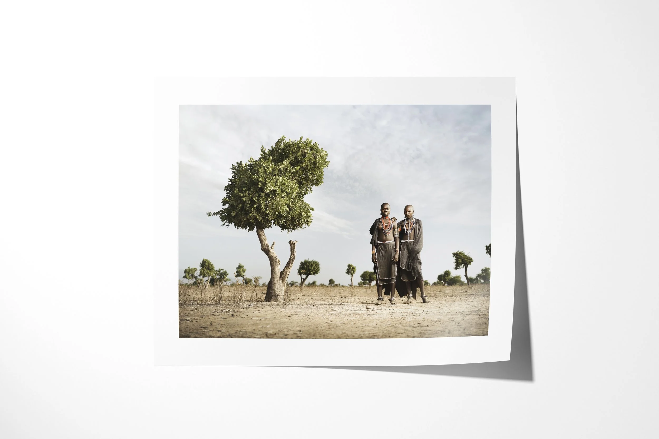 Fine art paper print of Rufa & Lago, showing two Arbore women standing together beneath a solitary tree in an arid landscape.