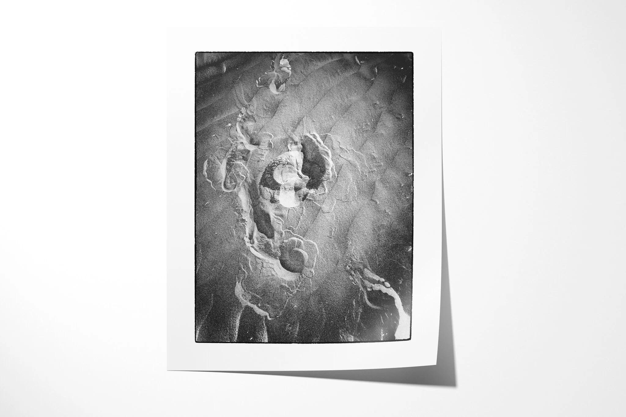Unframed fine art paper print of Imprint, featuring overlapping shoe impressions and scuffed marks pressed into a dark granular surface.