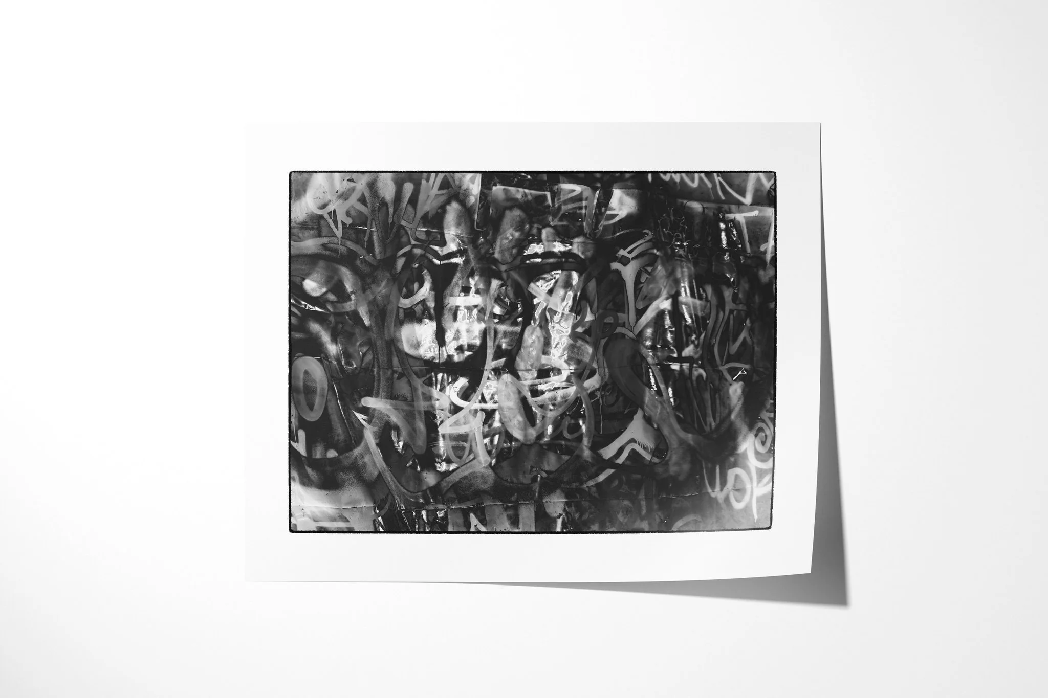 Fine art paper print of Impression I, showing a layered monochrome surface of looping graffiti-like marks, seams, reflections and partially recognisable figures.