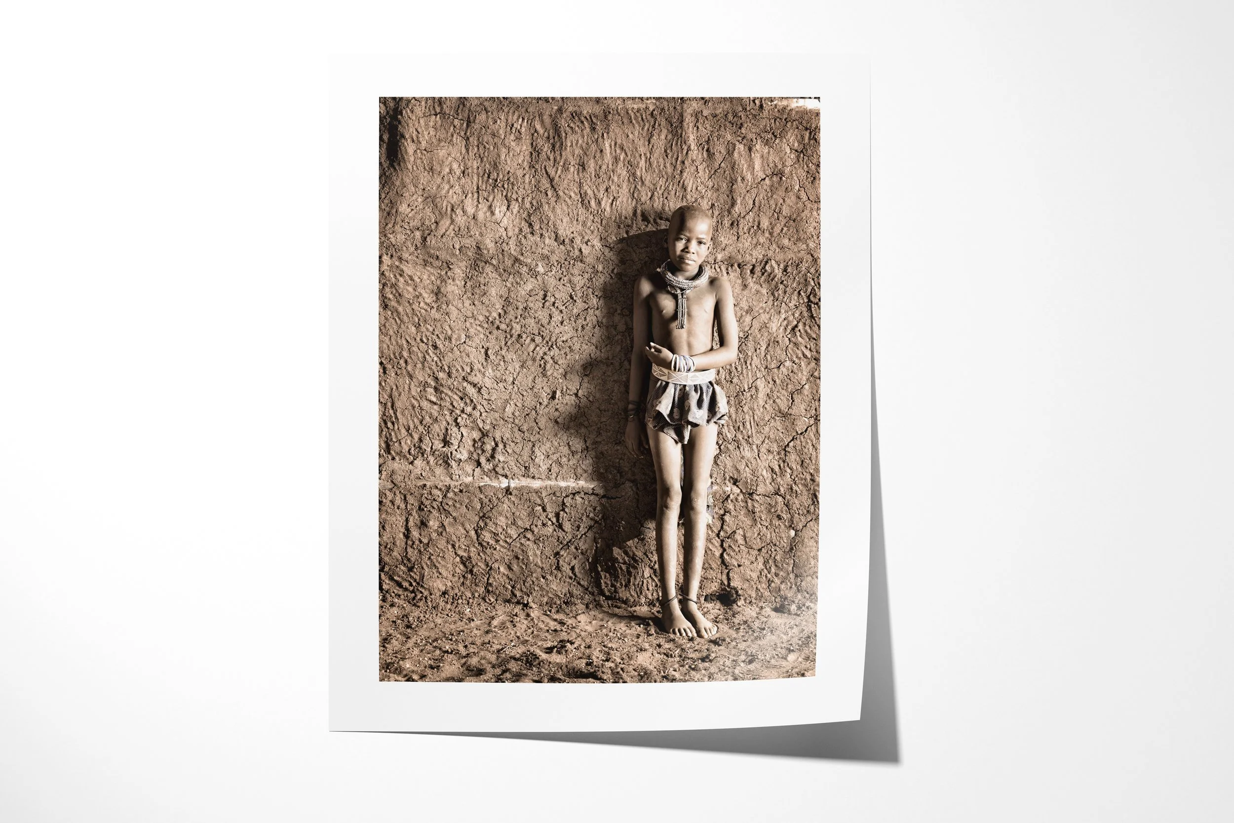 Fine art paper print of Potono, showing Potono standing against a textured earthen wall with a child’s close-cropped hairstyle.