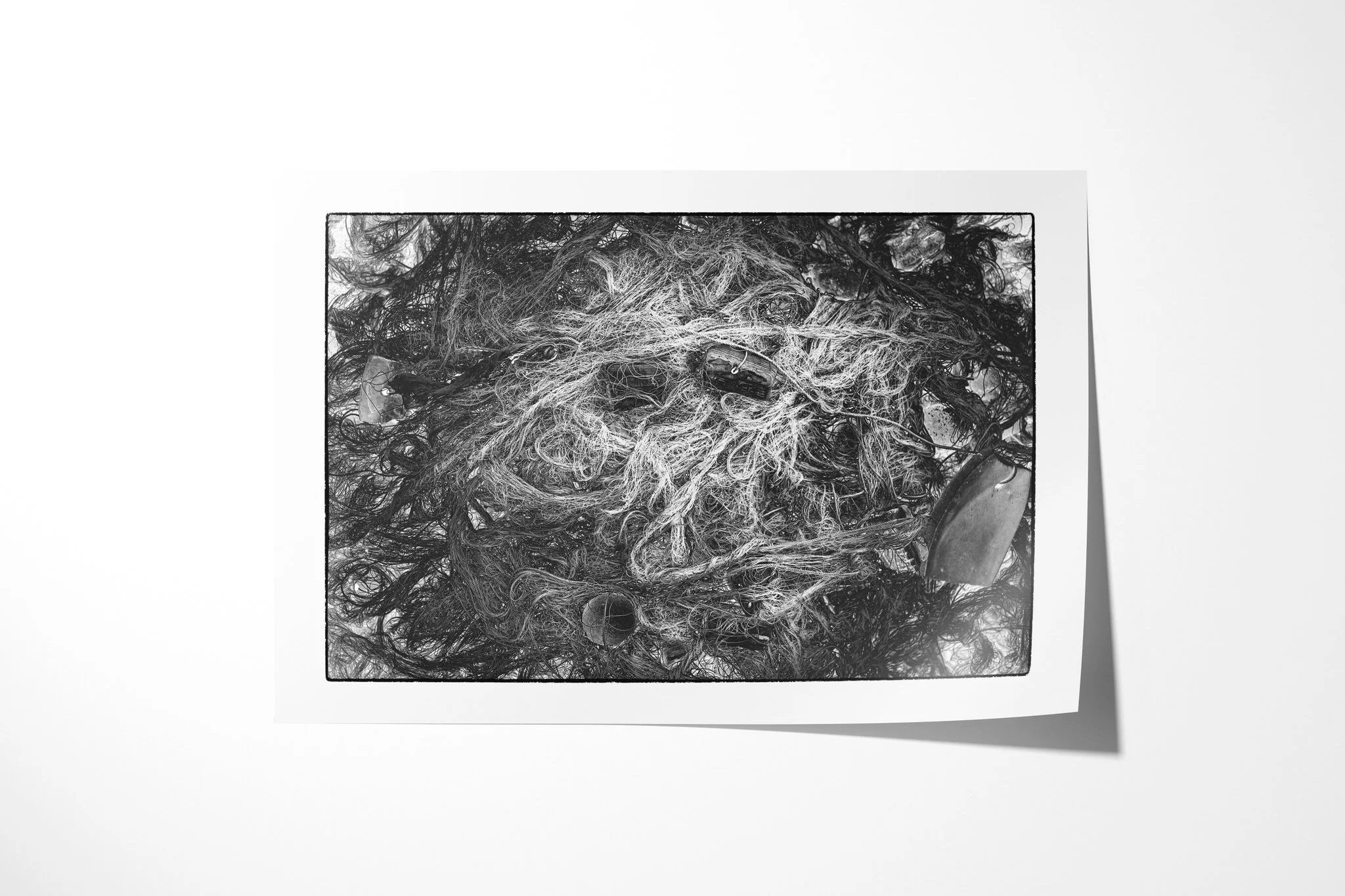 Fine art paper print of Tangle, showing a dense tangle of netting, fine cord, rope and scattered weathered fragments in black and white.