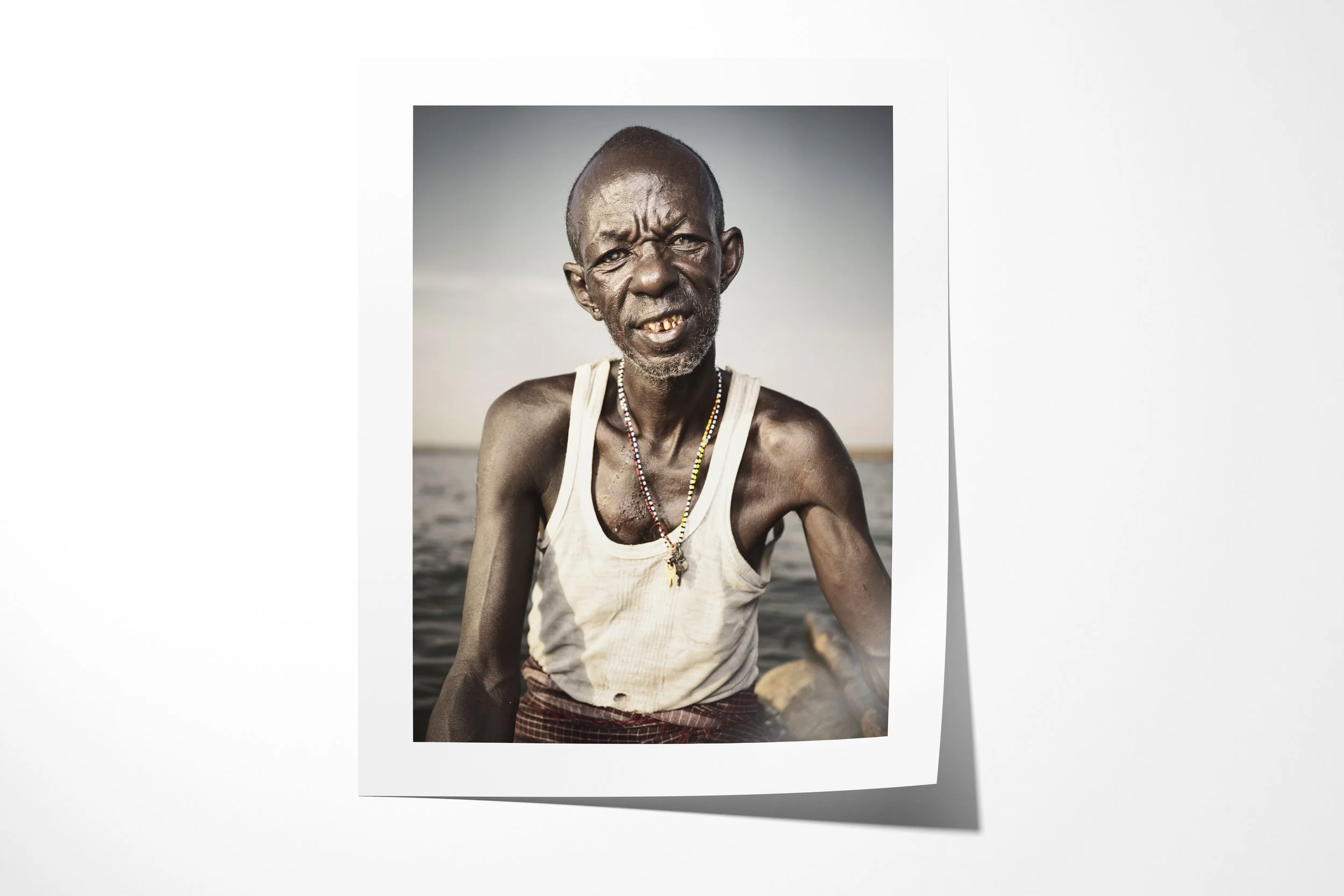 Fine art paper print of Lengutuk, showing a close portrait of an older El Molo fisherman beside the waters of Lake Turkana.