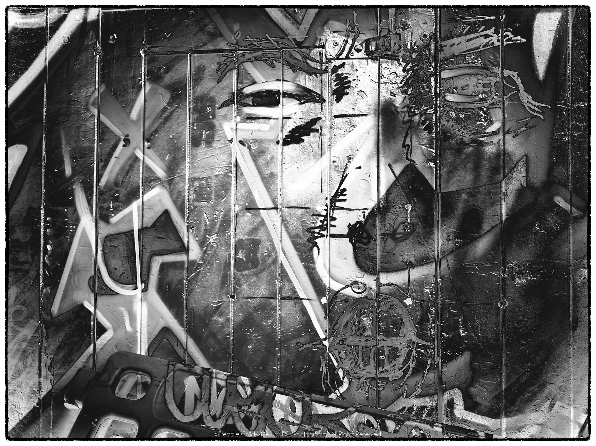 Stylised eye and face spanning a panelled monochrome surface with angular graffiti-like lines and symbols.