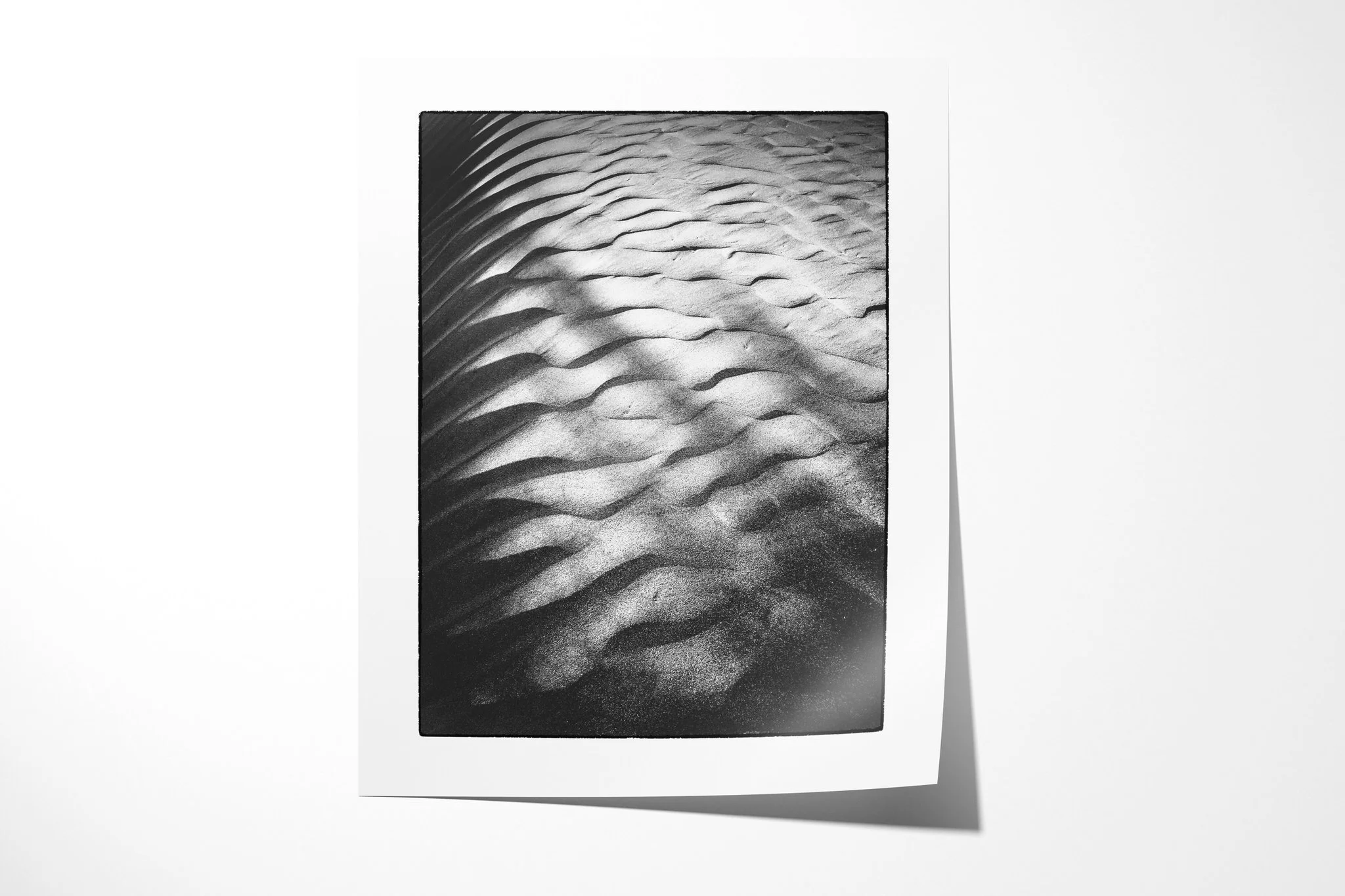 Ripple presented as an unframed fine art paper print, showing a close view of sand ripples with bright crests and deep shadows fading towards the top.