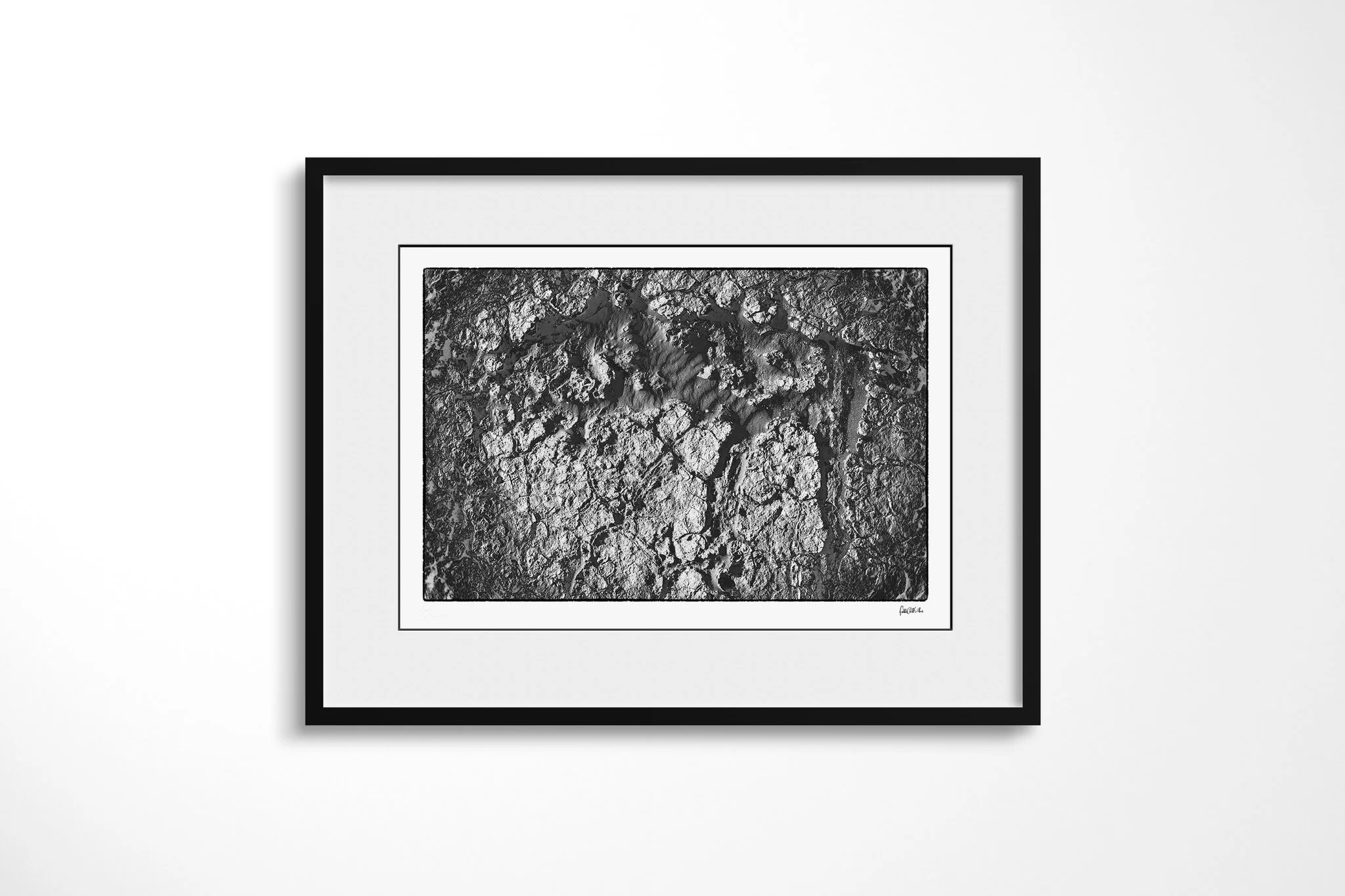 Khamsin V presented in a black frame and wide white mount, showing broken pale crust surrounding a smoother central opening of subtly rippled sand.