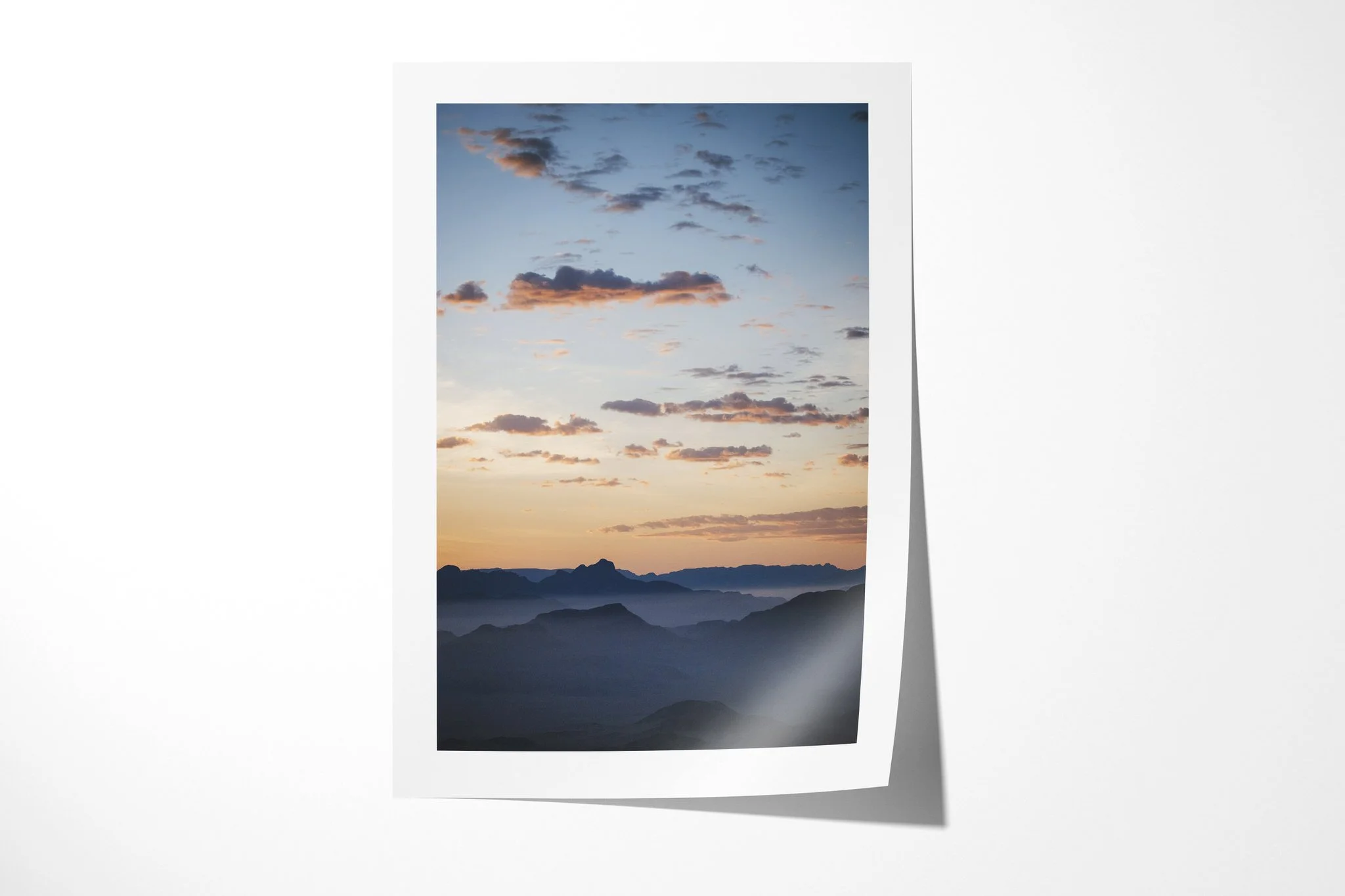 Fine art paper print of Sossusvlei Sunrise, showing layered dark desert ridges at Sossusvlei beneath peach and pale blue clouds at sunrise.