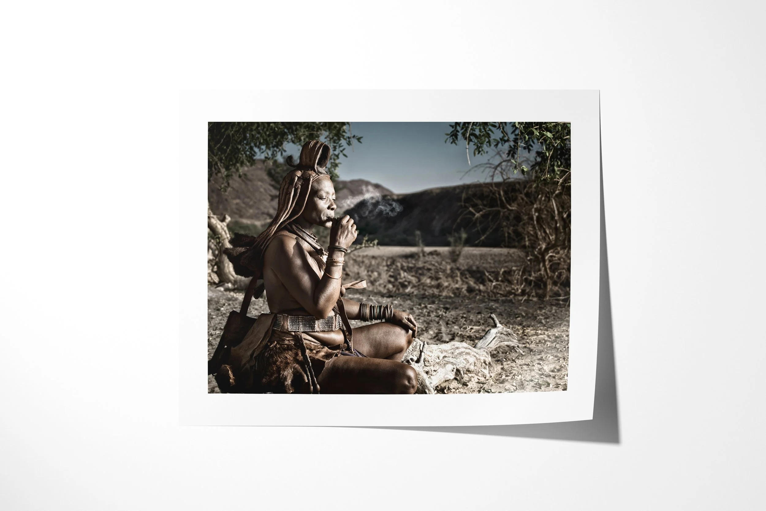 Fine art paper print of Ngorera, showing Ngorera seated beneath a tree smoking a small pipe in the dry Kunene landscape.