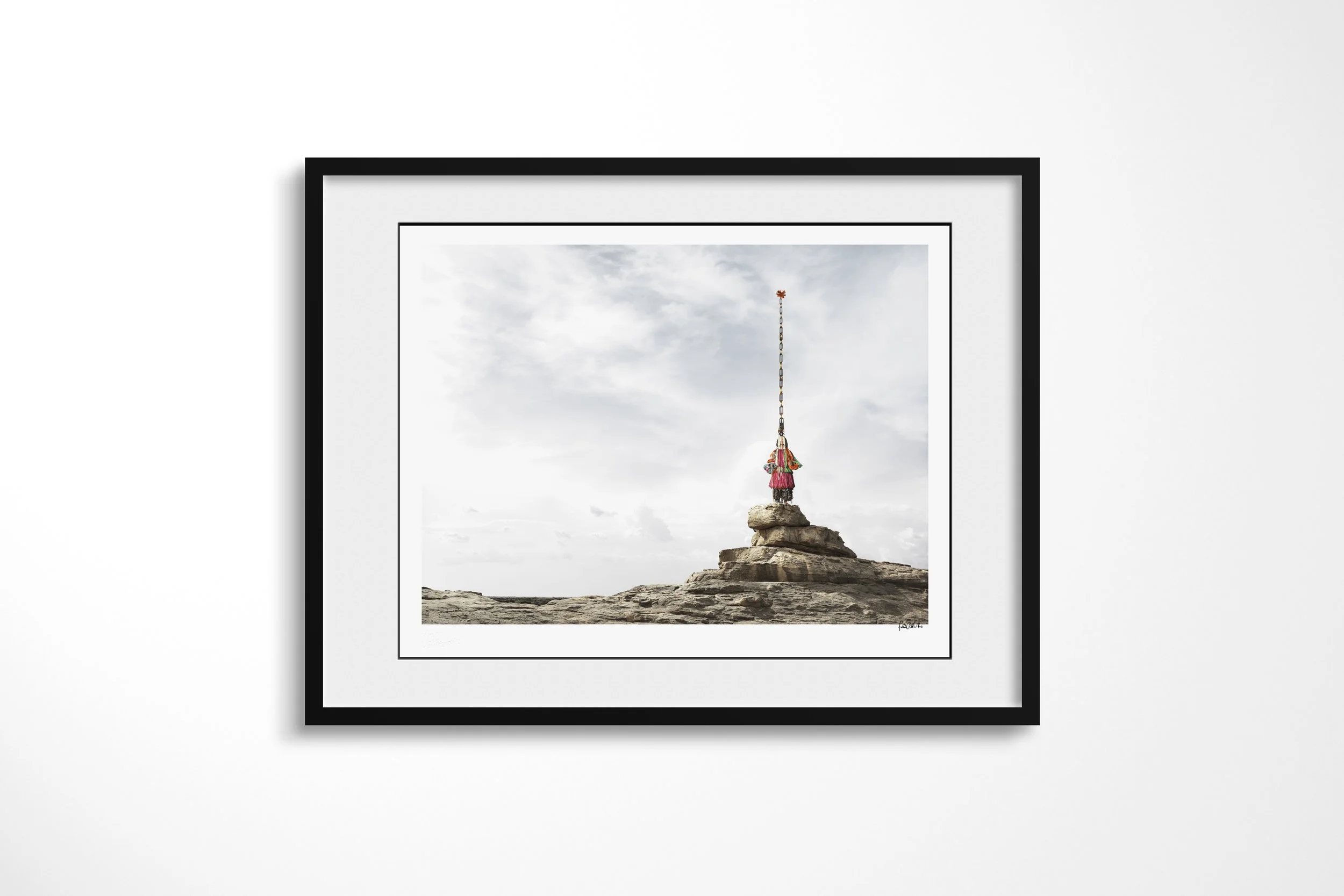 Framed presentation of Sirige (Mask) in a black frame and white mount, showing a Dogon Sirige mask with an exceptionally tall vertical superstructure standing on a rock pinnacle.