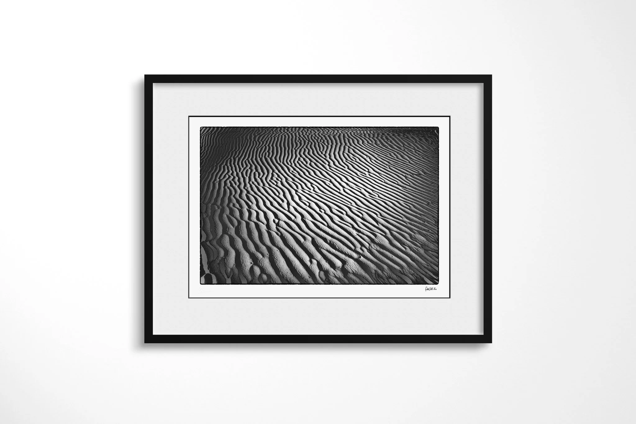 Framed presentation of Khamsin I in a black frame with a wide white mount, showing closely spaced sand ripples sweeping diagonally through alternating bands of light and shadow.