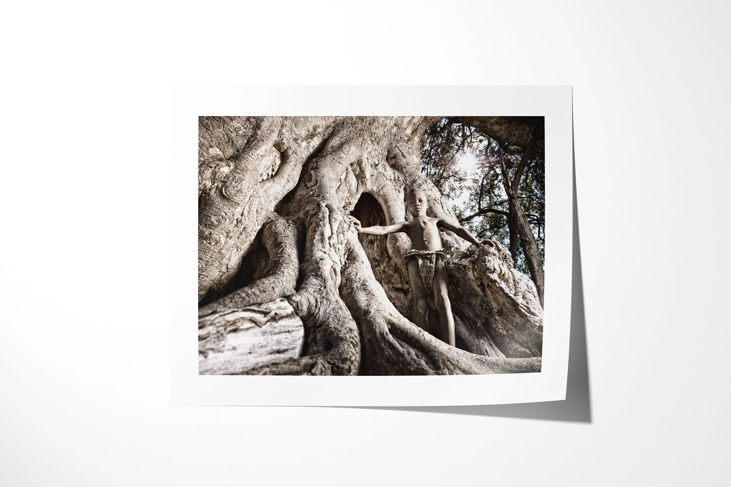 Fine art paper print of Kakoke, showing Kakoke standing inside the folded roots and hollow trunk of an immense fig tree.