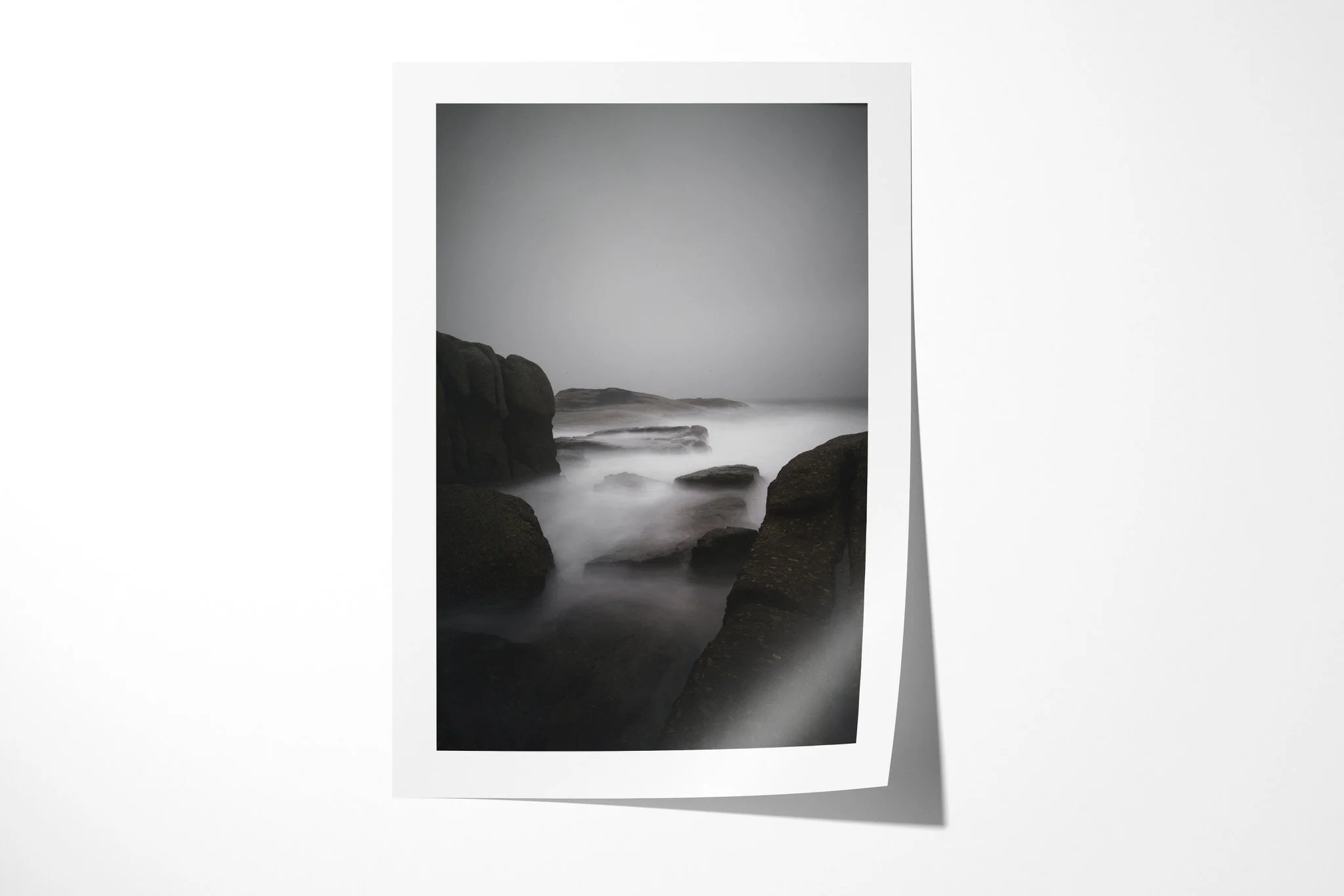 Fine art paper print of Misty Morning, showing dark coastal boulders framing pale long-exposure seawater beneath a blank grey mist.
