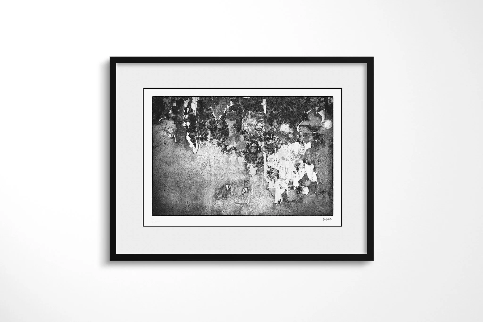 Black-framed presentation of Vestige with a wide white mount, featuring a weathered wall surface with pale peeling layers exposing dark floral patterning beneath.