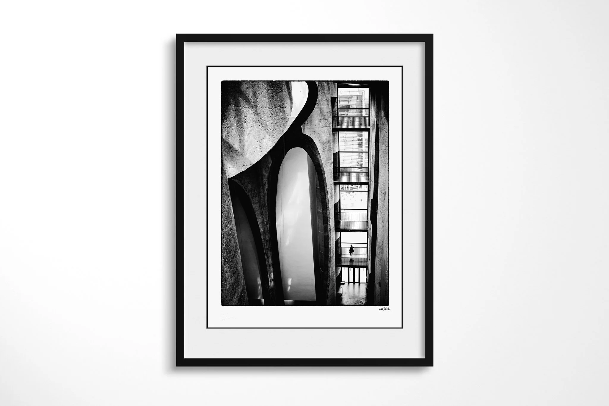 Black-framed fine art print of Organ Pipes with a white mount, showing monumental curved concrete forms beside stacked walkways, with a solitary figure visible in a high-contrast interior.