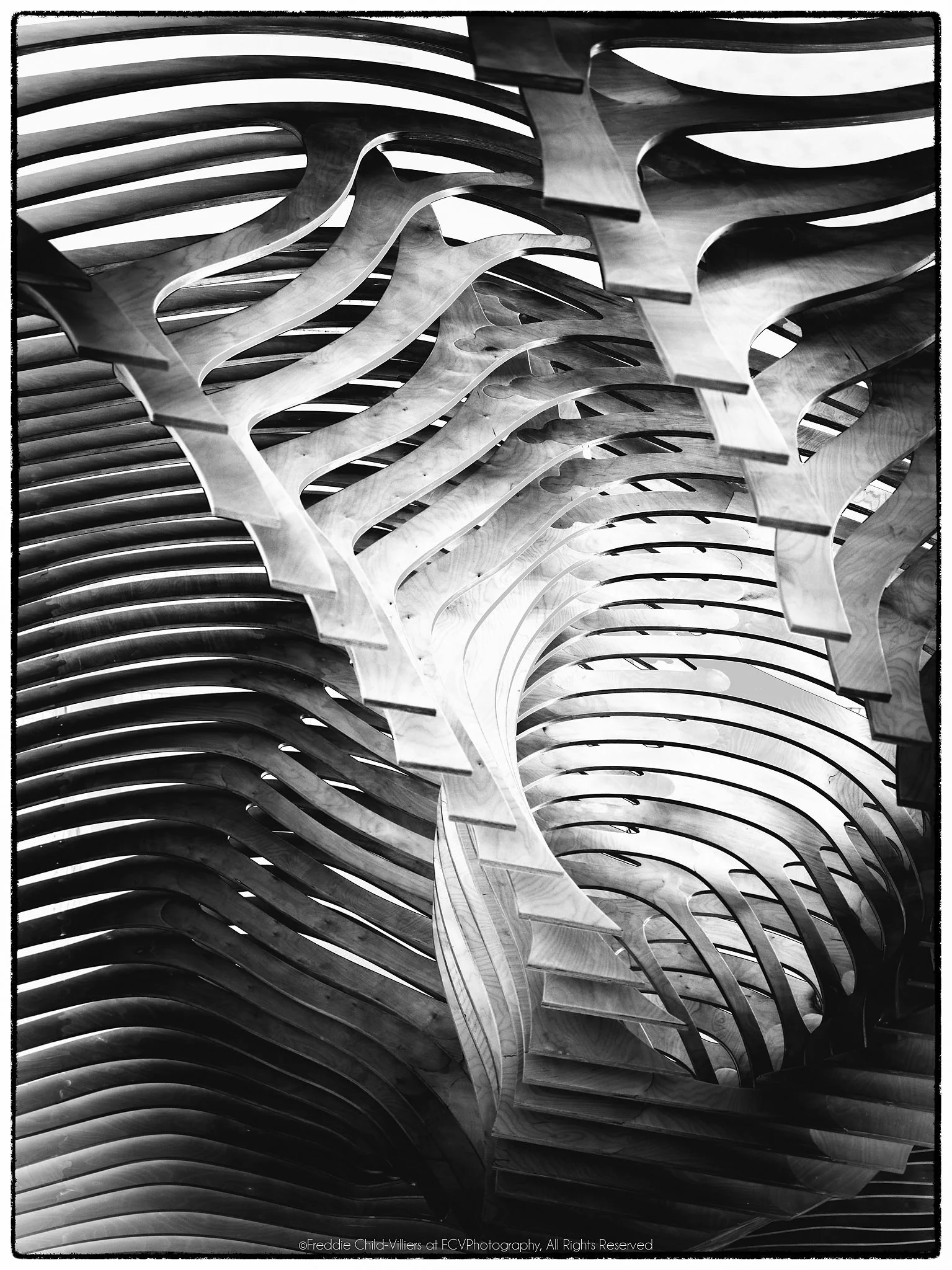 Repeating curved ribs and slatted bands forming a symmetrical high-contrast structure.