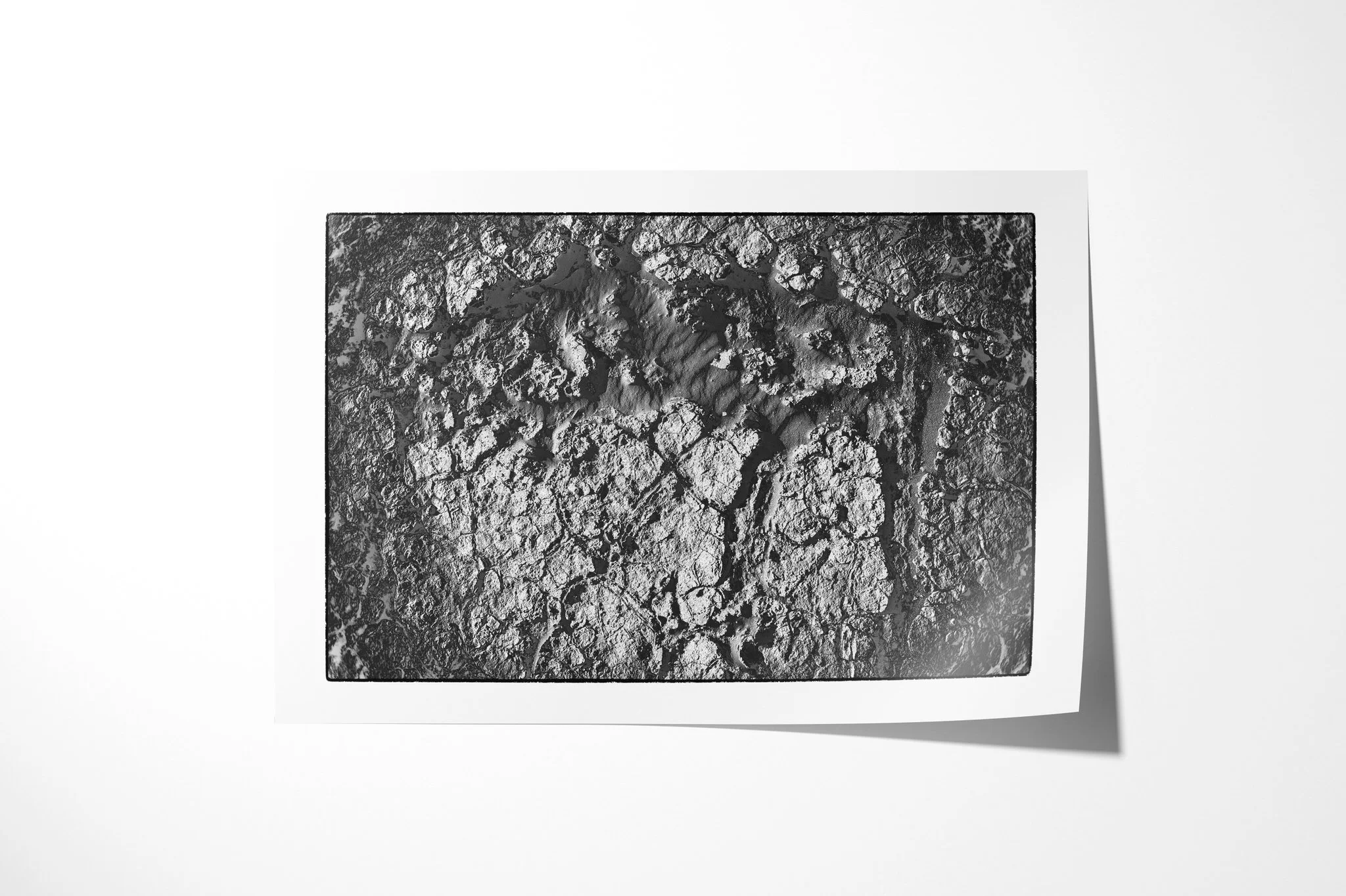 Khamsin V presented as an unframed fine art paper print, showing broken pale crust surrounding a smoother central opening of subtly rippled sand.