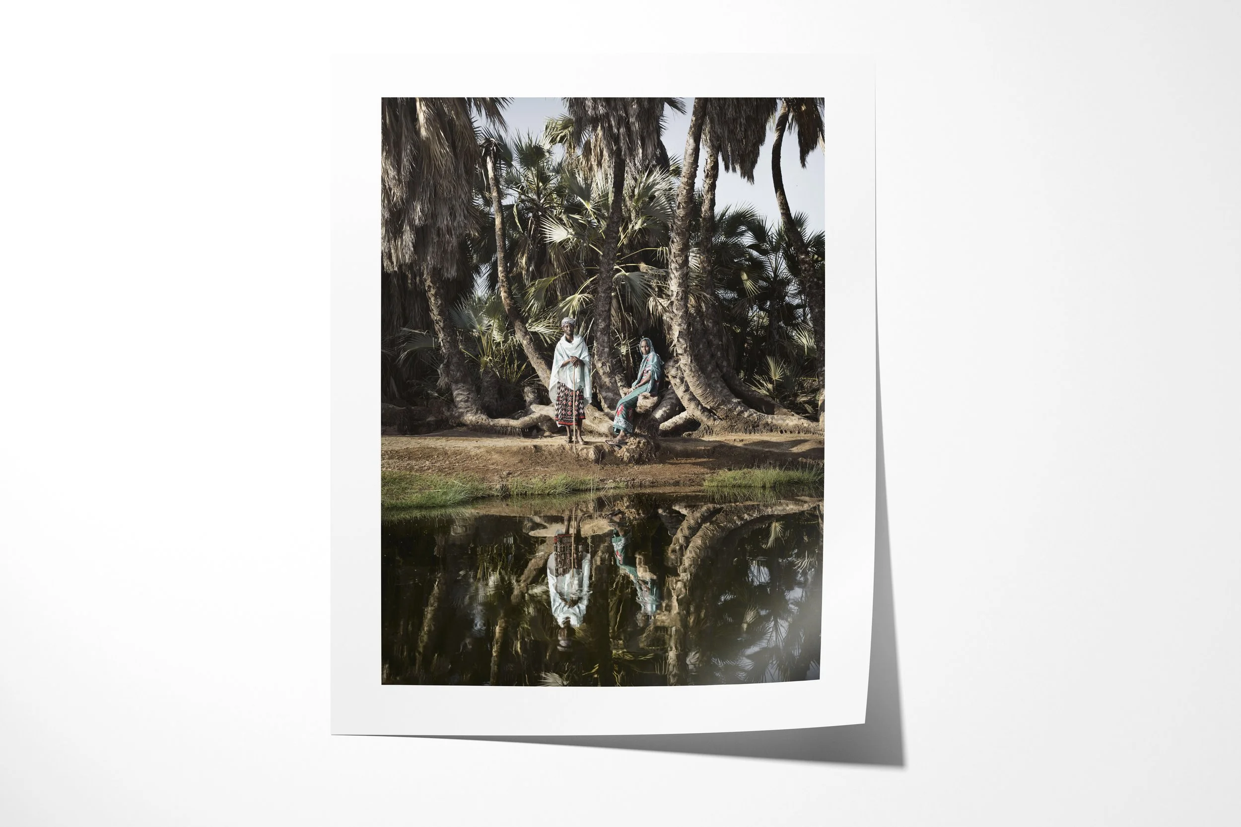 Fine art paper print of Talaso & Halkano II, showing Talaso and Halkano standing beside a still spring among dense doum palms.