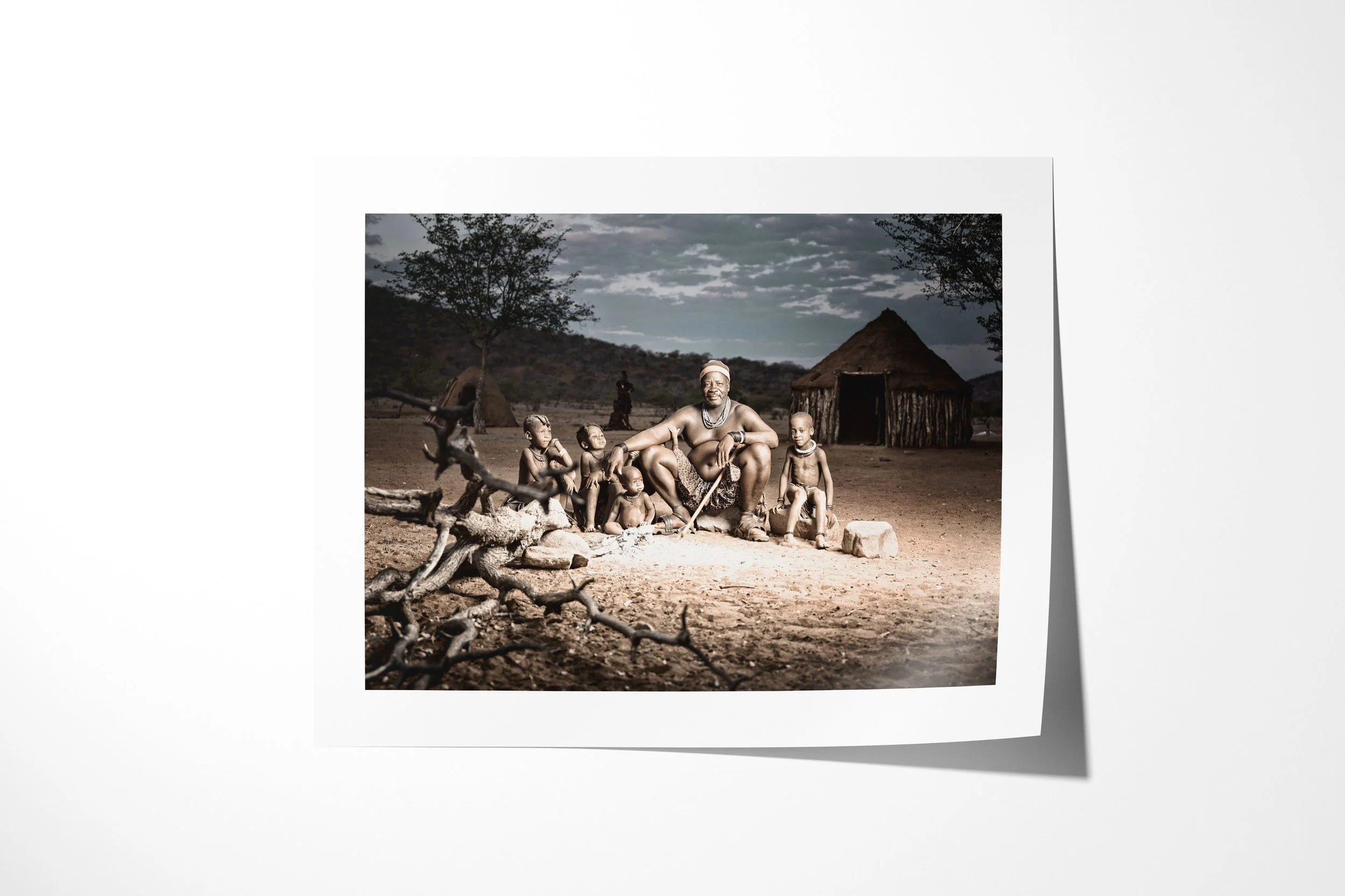 Fine art paper print of Chief Tjikoko, showing Chief Tjikoko seated with children beside the ancestral fire outside a conical Himba dwelling.