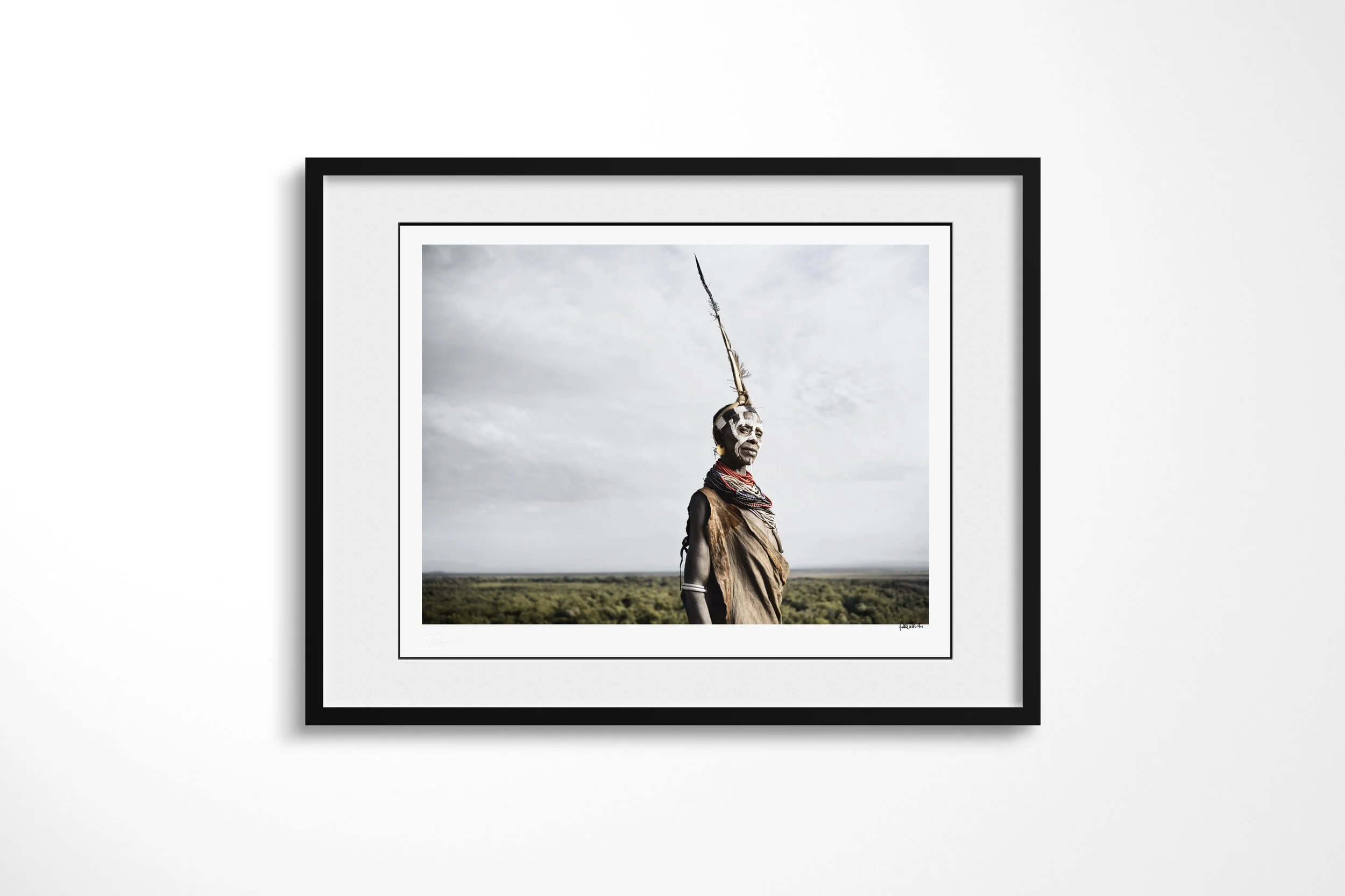 Framed presentation of Hayla in a black frame and white mount, showing a Kara woman in profile with facial paint, beadwork and a tall feathered headdress above the Omo Valley.