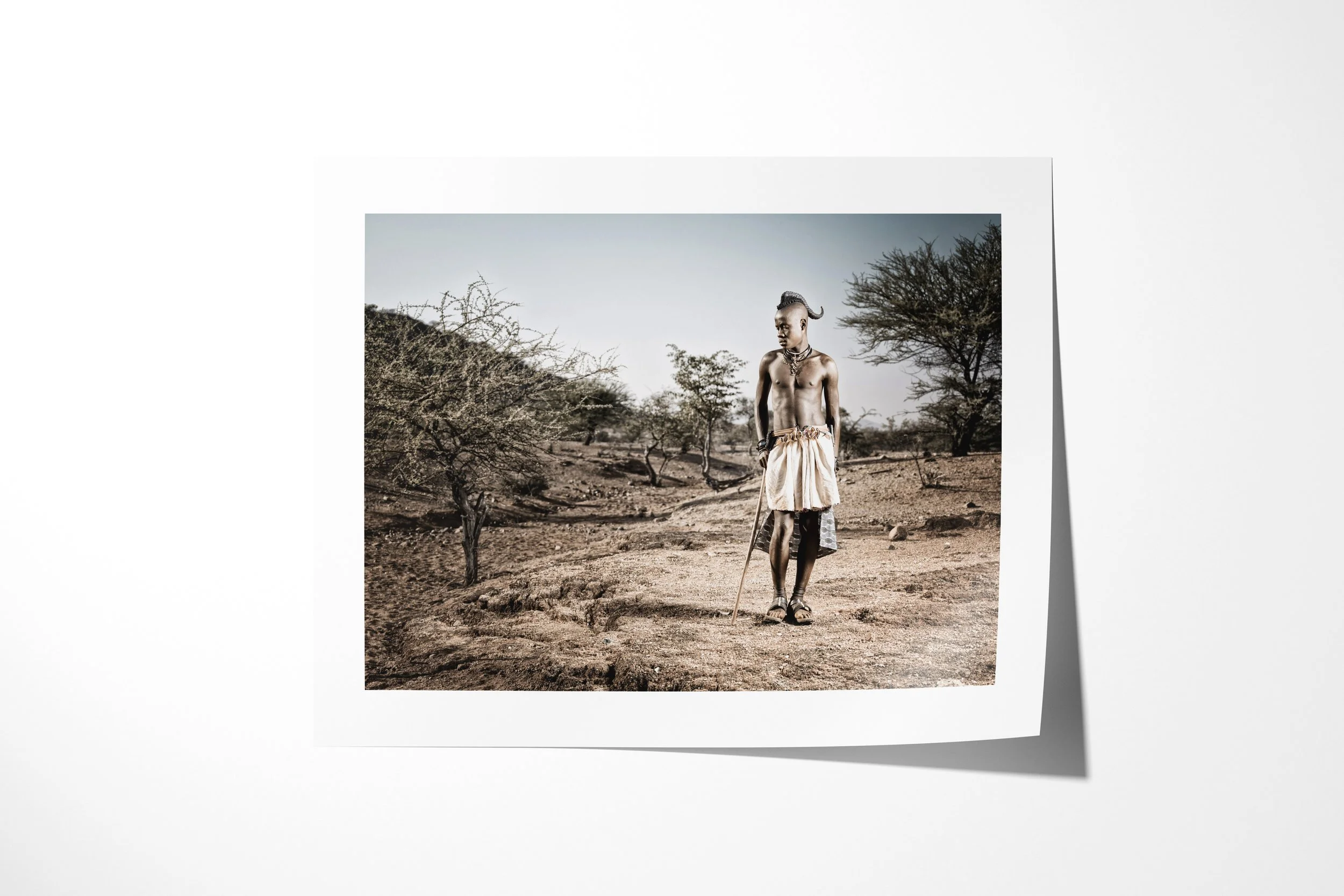 Fine art paper print of Hembinda, showing Hembinda holding a staff on a path through sparse dry woodland.
