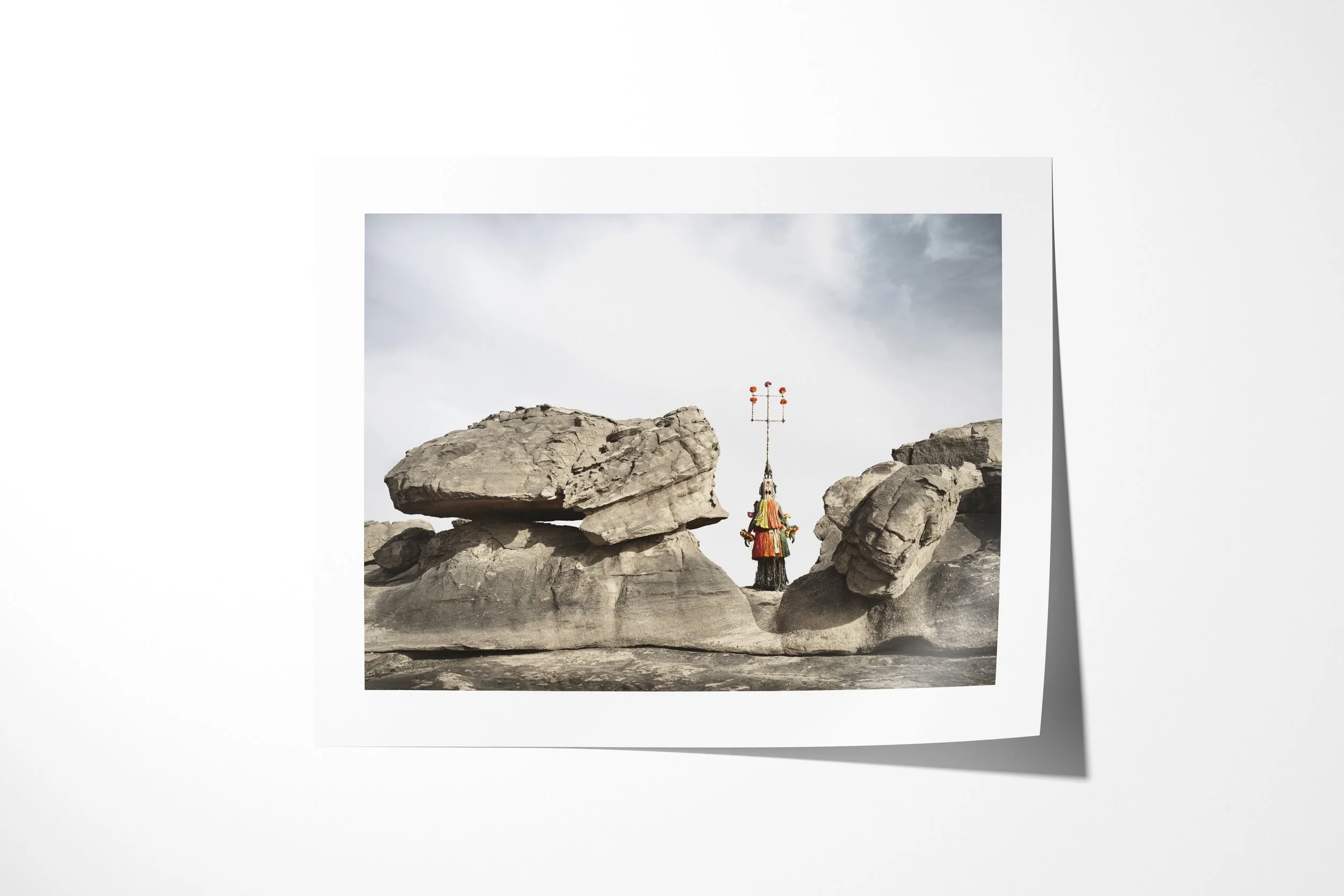 Fine art paper print of Karamagra (Mask), showing a tall Dogon Karamagra mask standing between massive boulders.