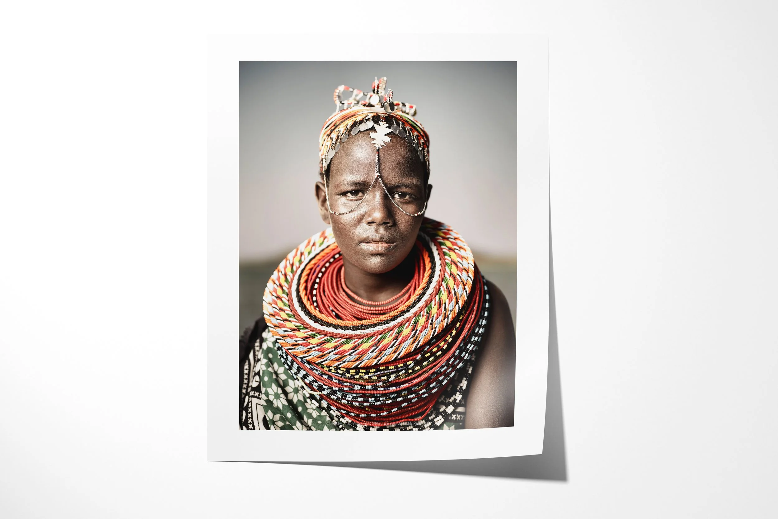 Fine art paper print of Nadirie, showing a close portrait of an El Molo woman wearing layered beadwork and fine chains across her face.