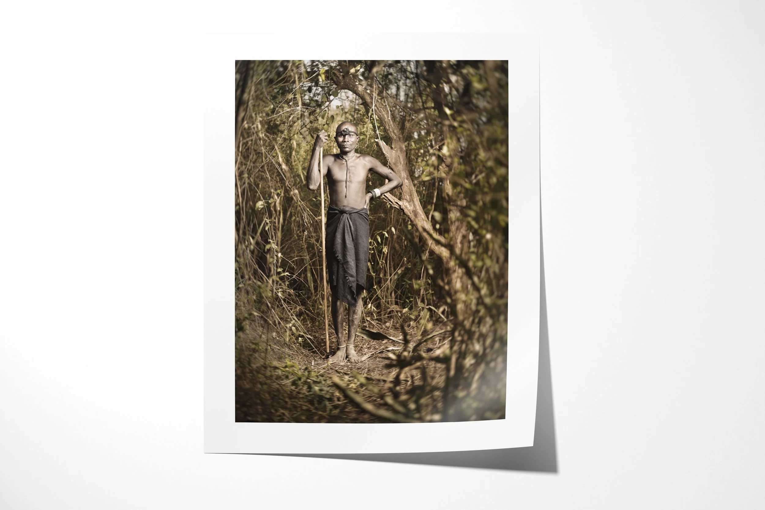 Fine art paper print of Lemoi, showing a Mursi man holding a long staff on a narrow path through dense woodland.