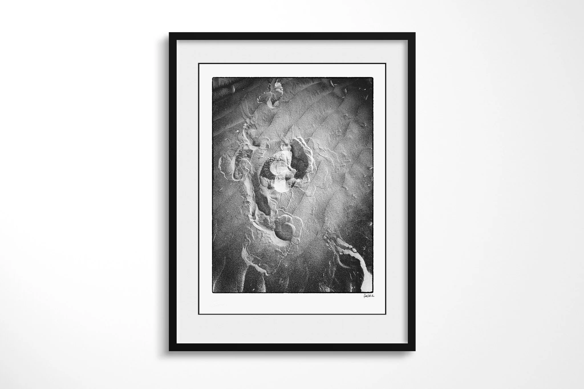 Black-framed presentation of Imprint with a wide white mount, featuring overlapping shoe impressions and scuffed marks pressed into a dark granular surface.