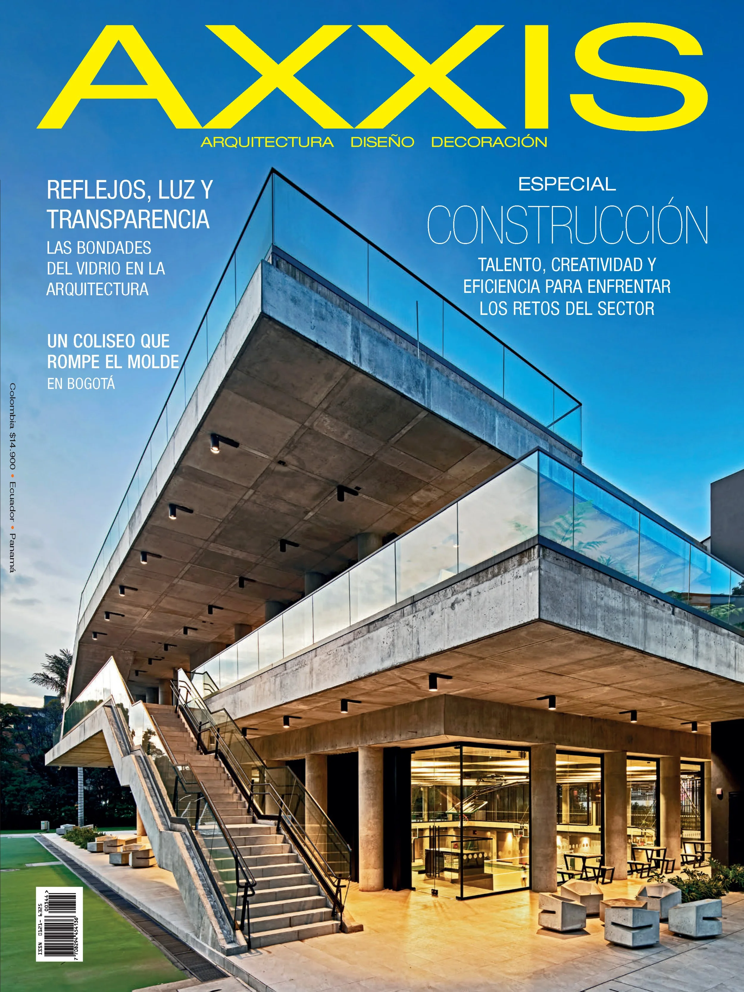 Portada de revista de arquitectura con edificio moderno de varias plantas, gran escalinata exterior, y ventanas de vidrio. El cielo es azul y la iluminación interior es cálida.