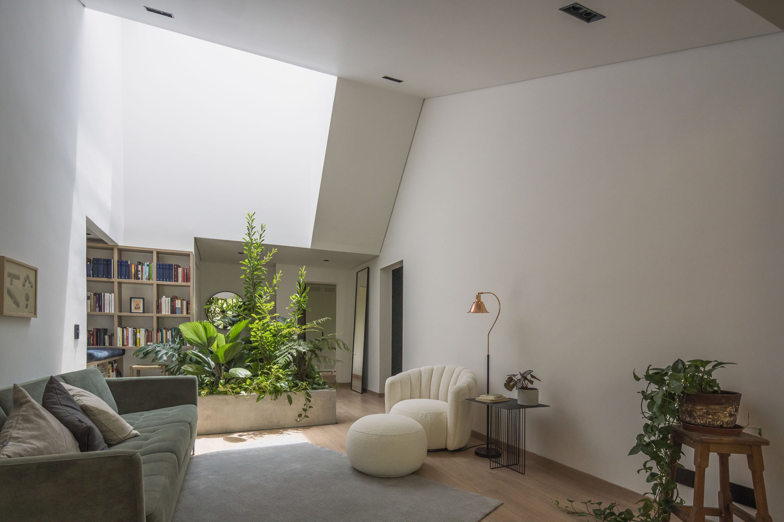 Sala contemporánea con luz natural de un tragaluz grande y jardines interiores. Guadalajara 602, una reforma diseñada en un apartamento en Medellín por TOLEDO Estudio de Arquitectura.