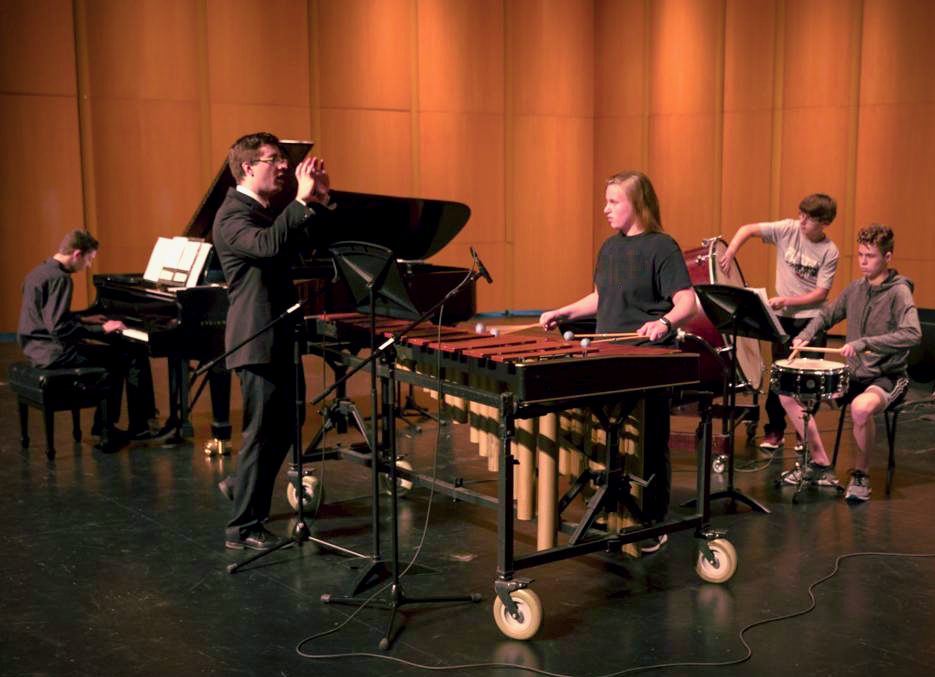 “Jon Nelson, second from left, talks to composer and pianist, Ryan Sellek, Bella Wineke, Jonathan Foster, Griffin Langhan, all 9th graders, and Jacob Couch, 11th grade, during a rehearsal of Resonance 2018 at the Sun Prairie Performing Arts Center. Sellek’s composition is titled, “The Sunken Meadows March.” ANDY MANIS, FOR THE STATE JOURNAL” (Source: Wisconsin State Journal)