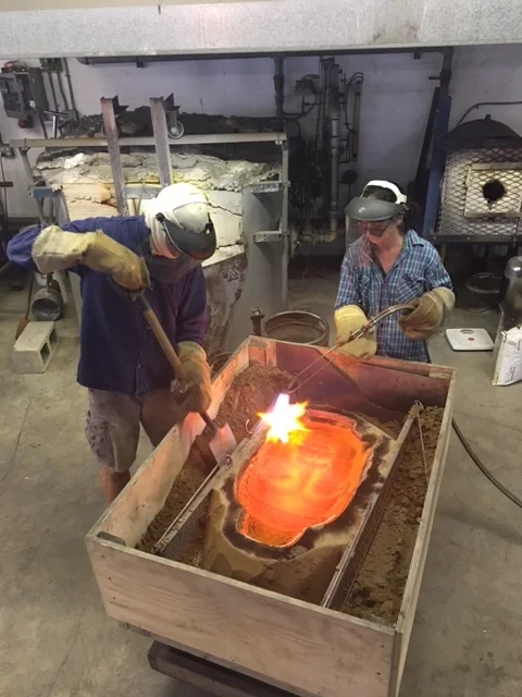 Marlene torches the glass while her husband, Thomas, cuts away the excess portion of the sand mold