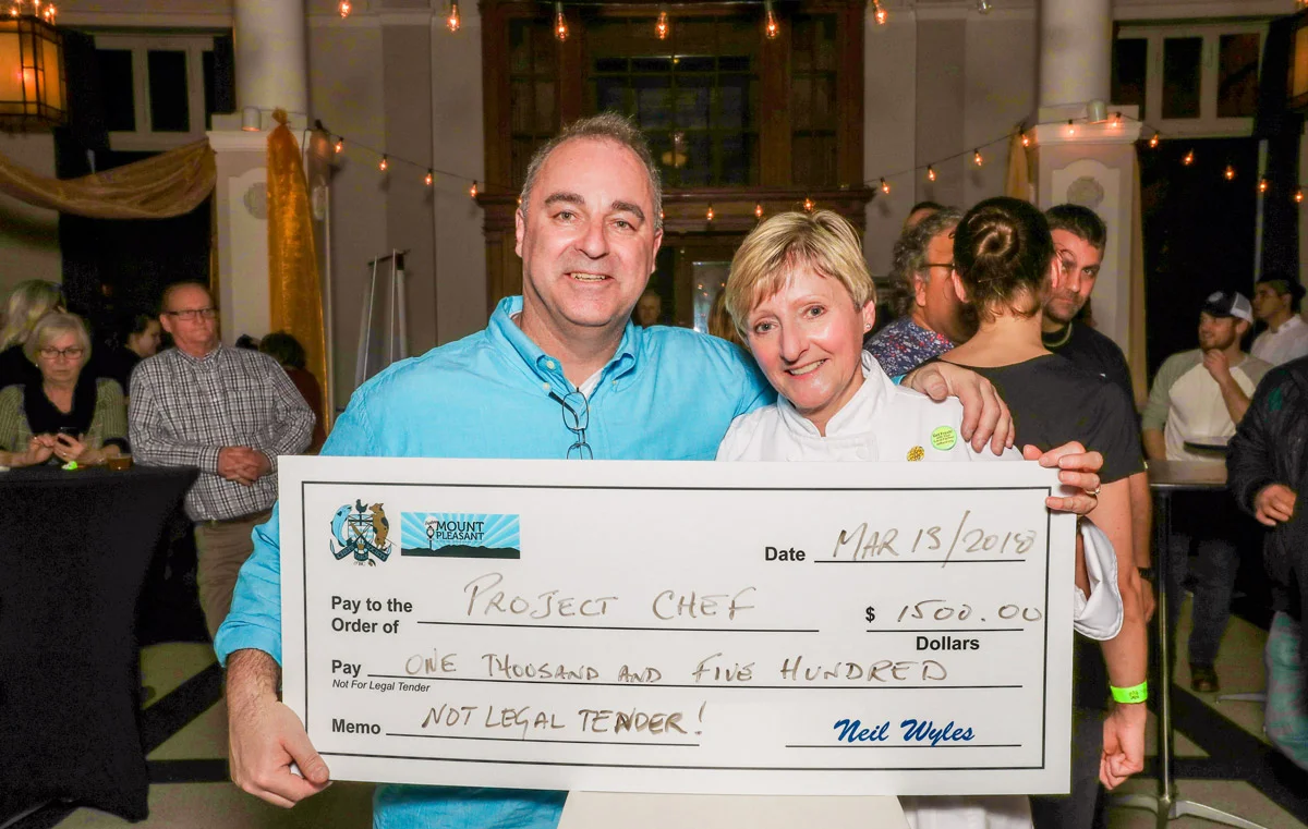 Curry Cup chair Neil Wyles of the Chefs' Table Society of BC and Mount Pleasant BIA presents Barb Finley of Project Chef $1500. Photo Credit Charles Zuckermann