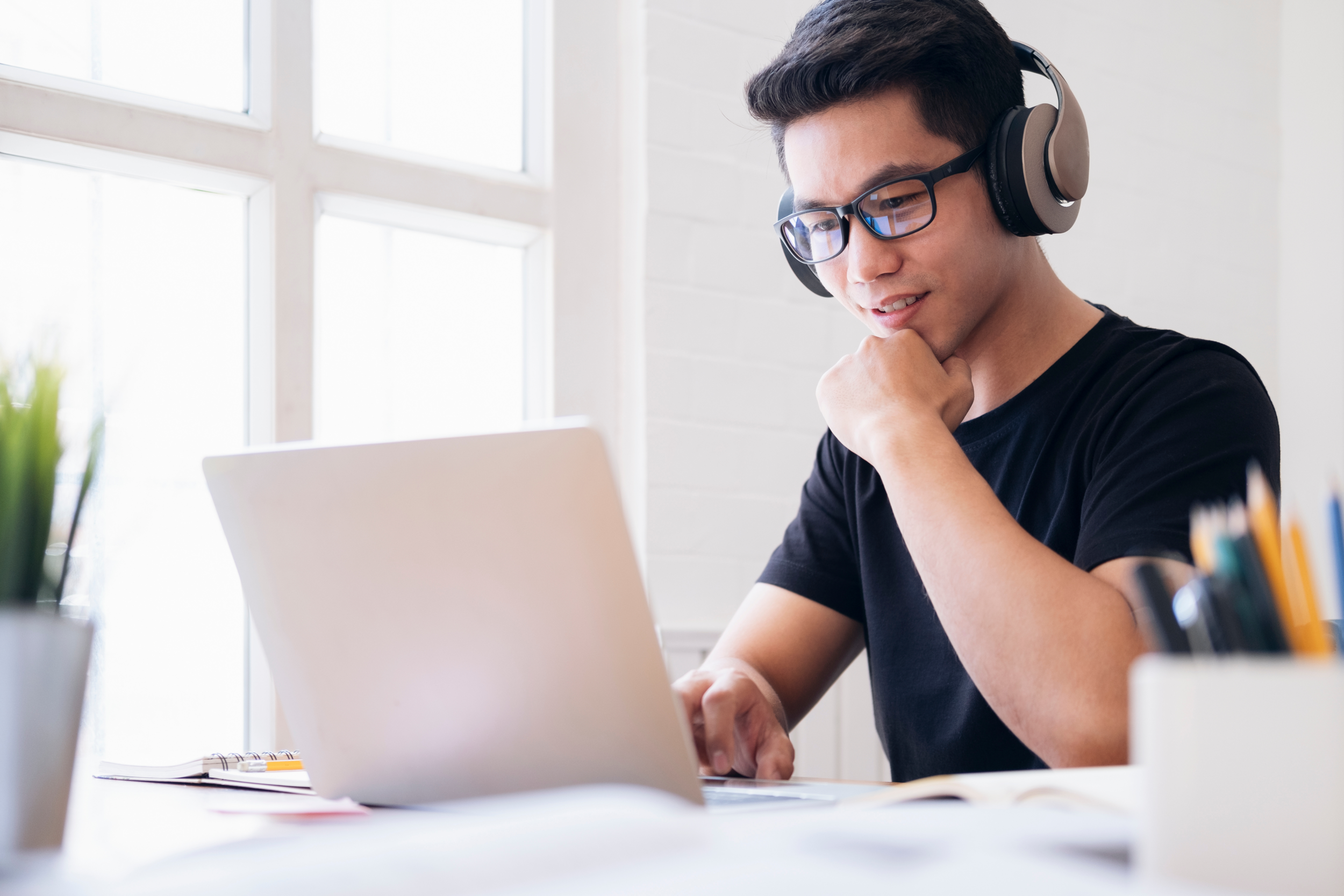 Teenager with glasses uses laptop