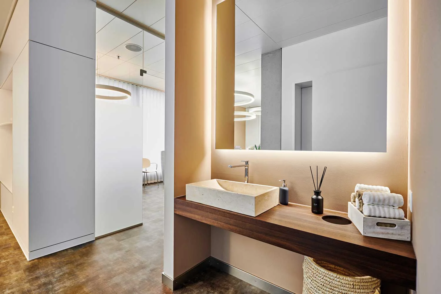 Abgeschirmte Beauty- Ecke mit warmweisser indirekter Beleuchtung, zusätzlich unterstützt durch den Erdton der Wand, ergibt eine angenehme und blendfreie Ausleuchtung des Bereichs.