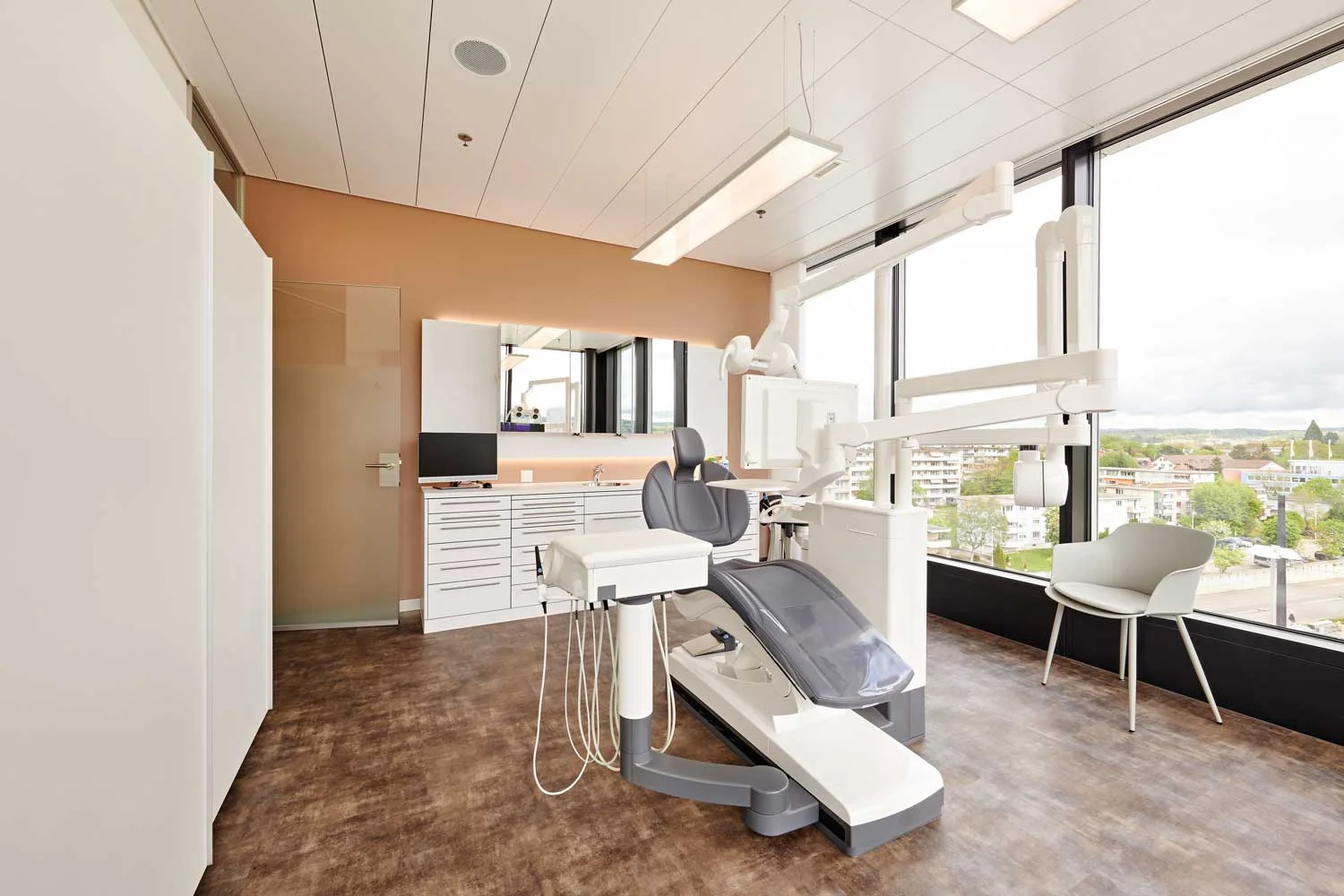 Alle Behandlungszimmer haben einen freien Blick auf die Umgebung. Die kaltweisse Beleuchtung des Zimmers verbindet sich optimal mit dem noch kühleren Tageslicht des Aussenraums.