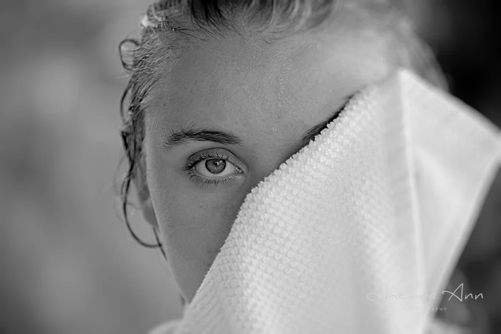 Summer time down by the pool, black and white portrait of beautiful girl drying her eye.
