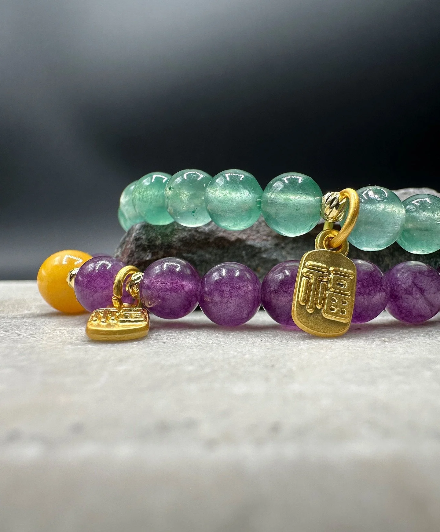 The BKB Prosperity Gem Bracelets blend natural energy with refined design. Crafted from green aventurine for luck and growth and amethyst for clarity and protection, each bracelet is finished with a gold-plated mini 福 (F&uacute;) charm, symbolizing b