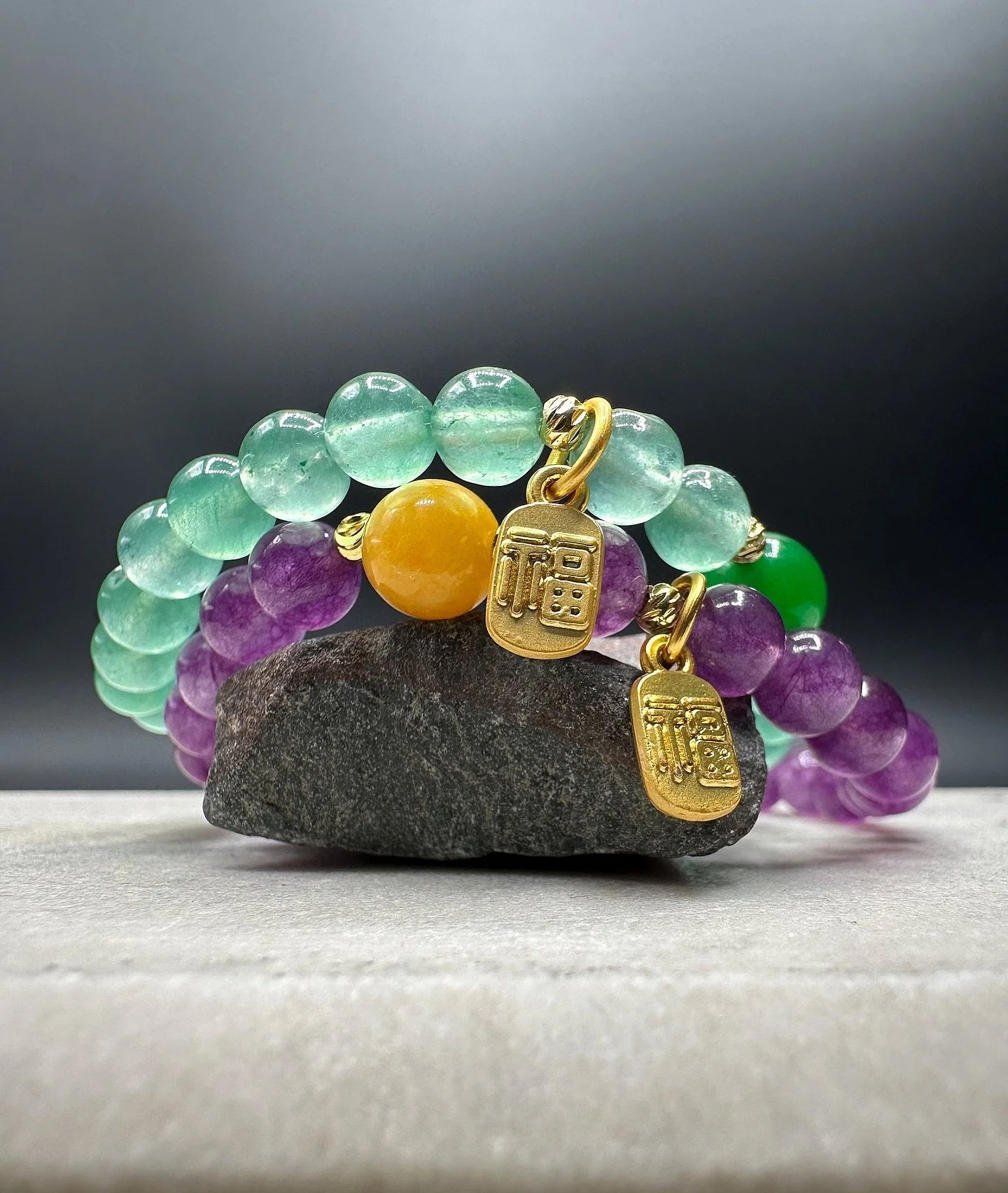 The BKB Prosperity Gem Bracelets blend natural energy with refined design. Crafted from green aventurine for luck and growth and amethyst for clarity and protection, each bracelet is finished with a gold-plated mini 福 (F&uacute;) charm, symbolizing b