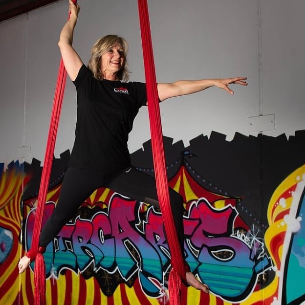 Guest hanging on red aerial silks