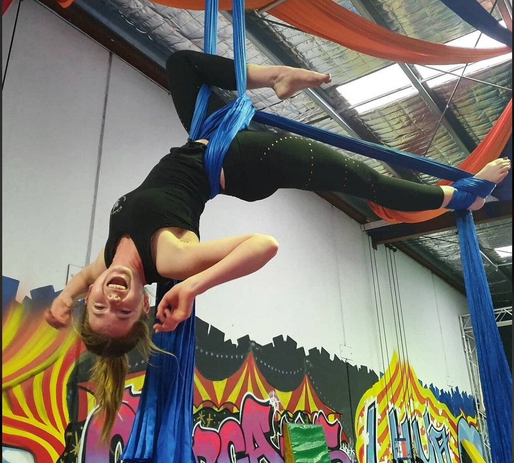 Child hanging upside down on aerial silks in the CircArts studio
