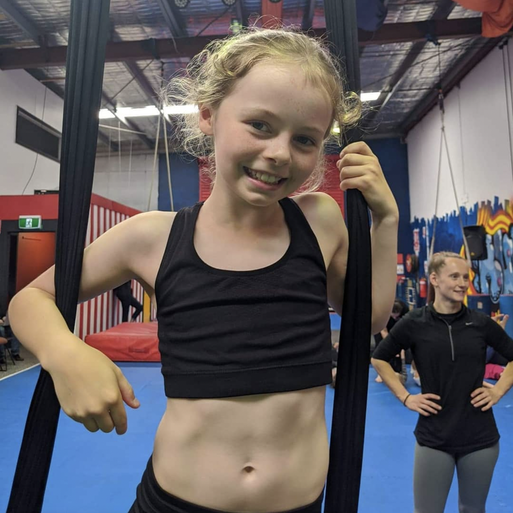Smiling girl holding aerial silks in the CircArts studio