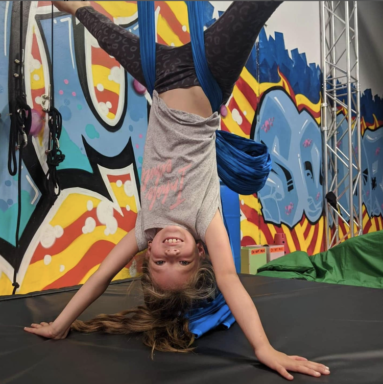 Child inverted on aerial silks