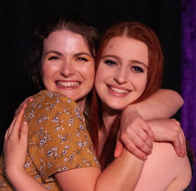 Two adult CircArts students hugging and laughing after their showcase