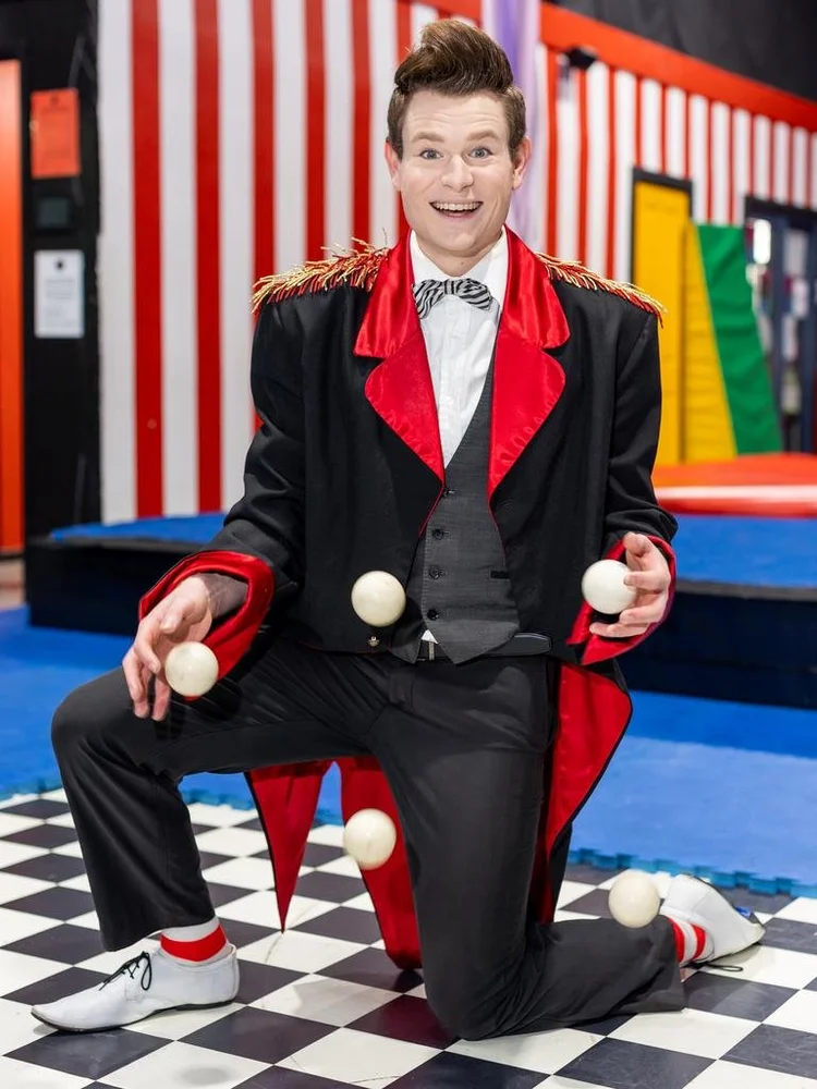 CircArts ringmaster performer juggling in a red tailcoat