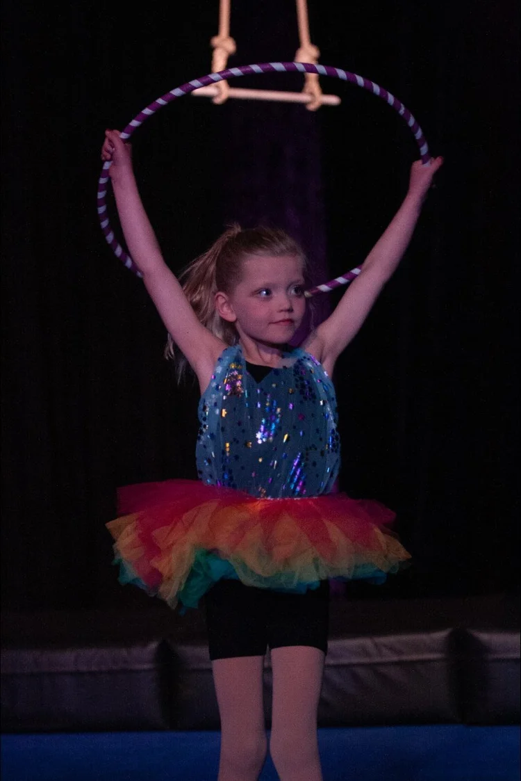 Young performer with arms raised on stage