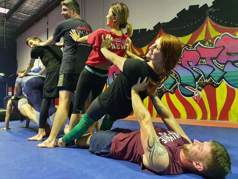 Adults laughing during a partner acrobatics team challenge