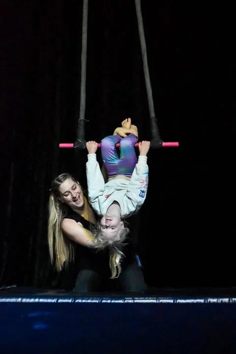 Coach spotting a student on the trapeze