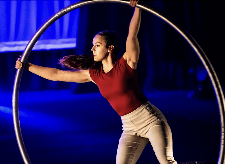 Performer spinning in a cyr wheel under blue stage lights