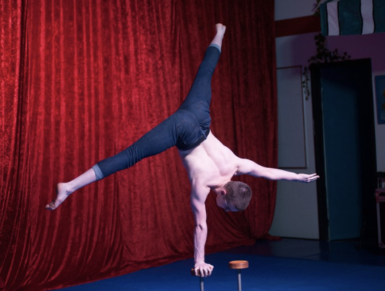 Hand balancer holding a one-arm handstand on stage