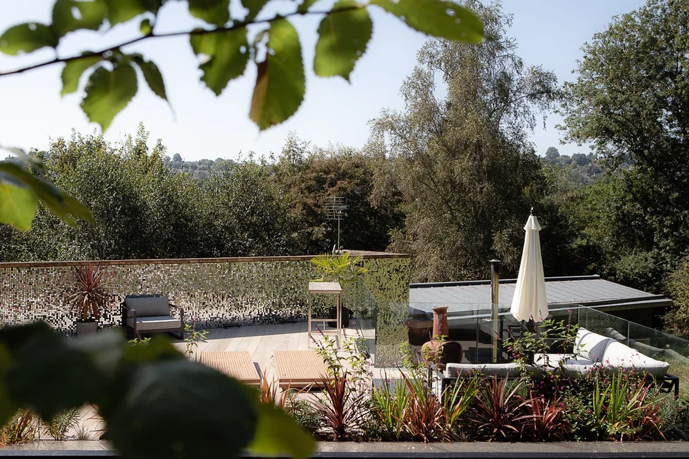 Roof terrace with decking, seating and hot-coloured planting above the treetops